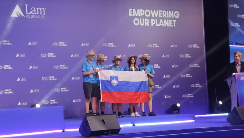 predstavitev slovenske ekipe na odru. Pred sabo držijo razvito slovenko zastavo