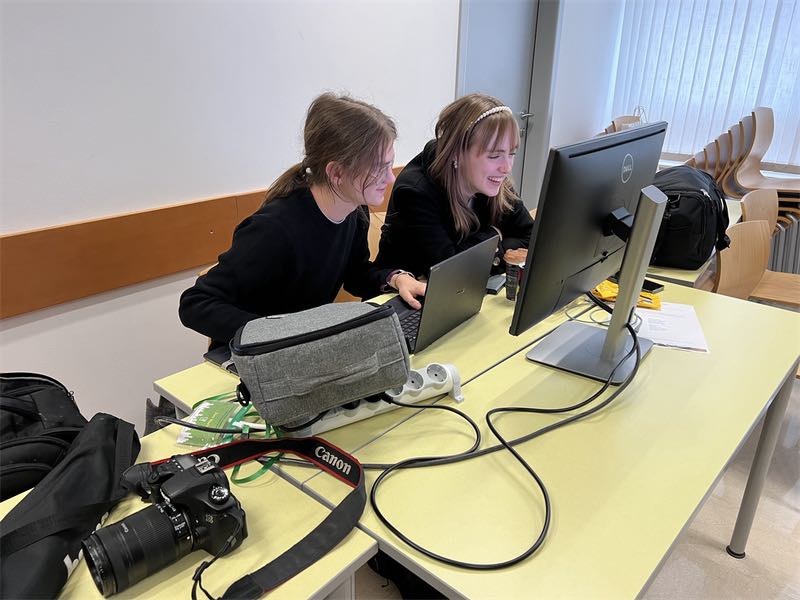 Nasmejana Tia Udovičić in Jure Maček pred računalnikom pri reševanju naloge