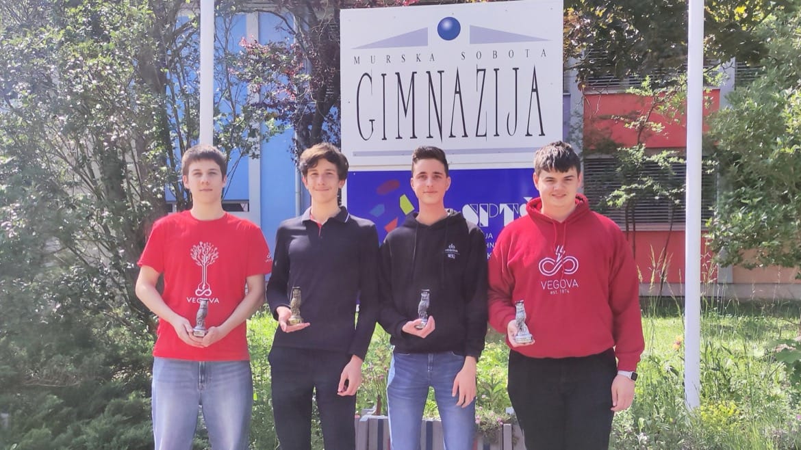 štirje dijaki pred napisom Murska Sobota gimnazija; vsak drži v roki nagrado; za njimi je travnata površina in modro-rdeča stavba
