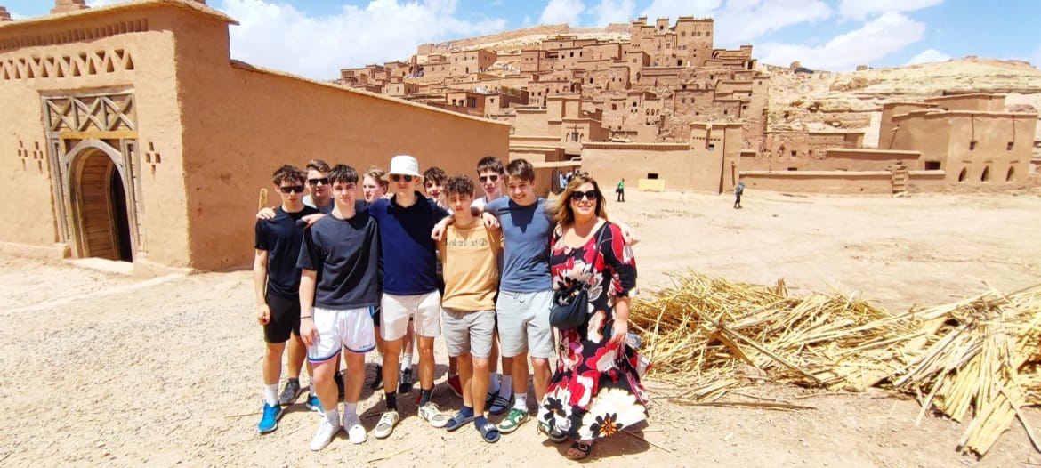 Dijaki s profesorico slikani pred prizoriščem filma Gladiator Ait Benhaddou. V ozadju puščava in na vzpetini puščavsko mesto.
