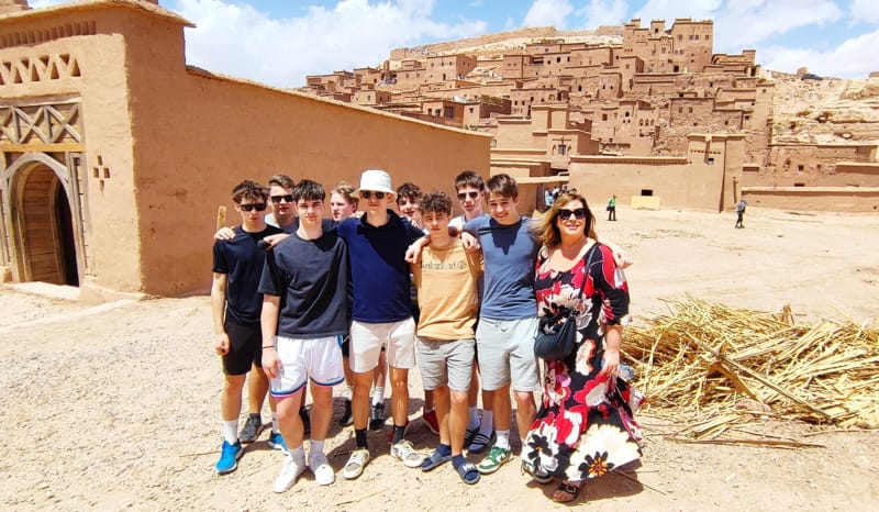 Dijaki s profesorico slikani pred prizoriščem filma Gladiator Ait Benhaddou. V ozadju puščava in na vzpetini puščavsko mesto.