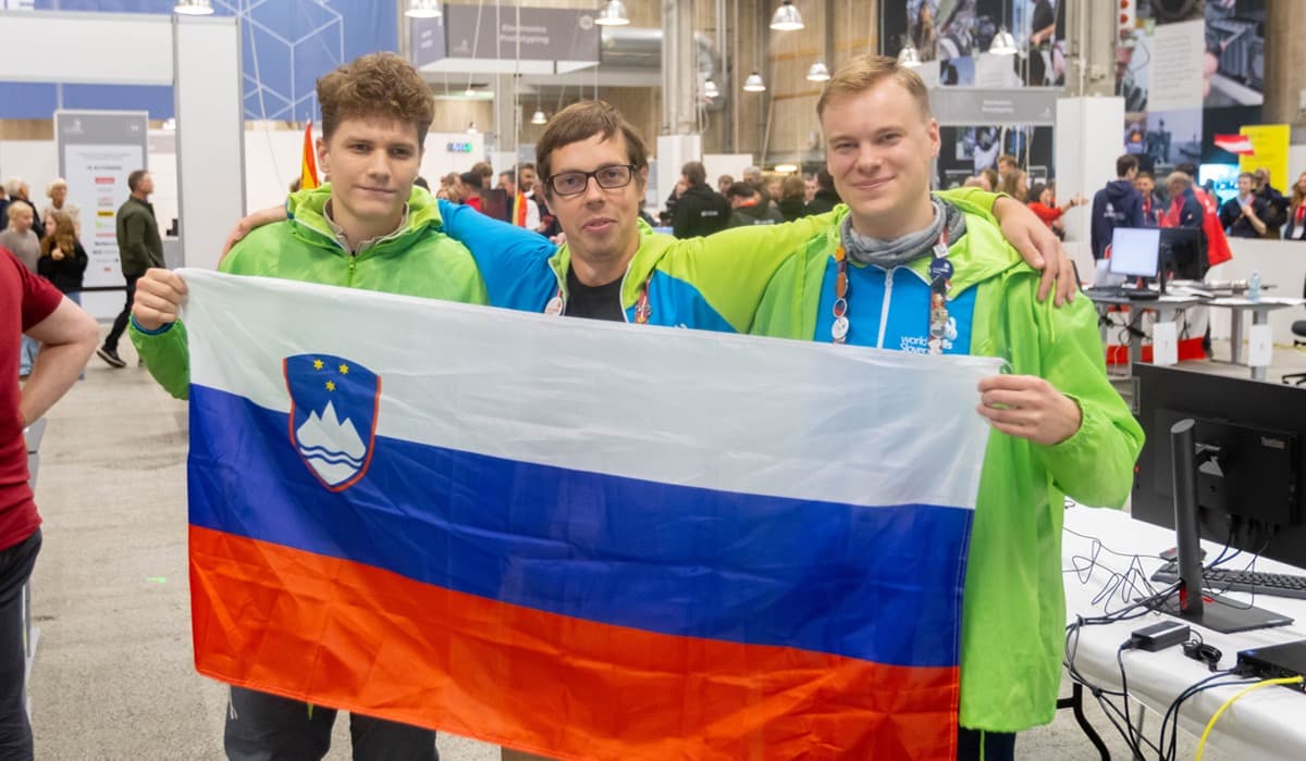 trije nasmejani tekmovalci Vegove z razprto slovensko zastavo.