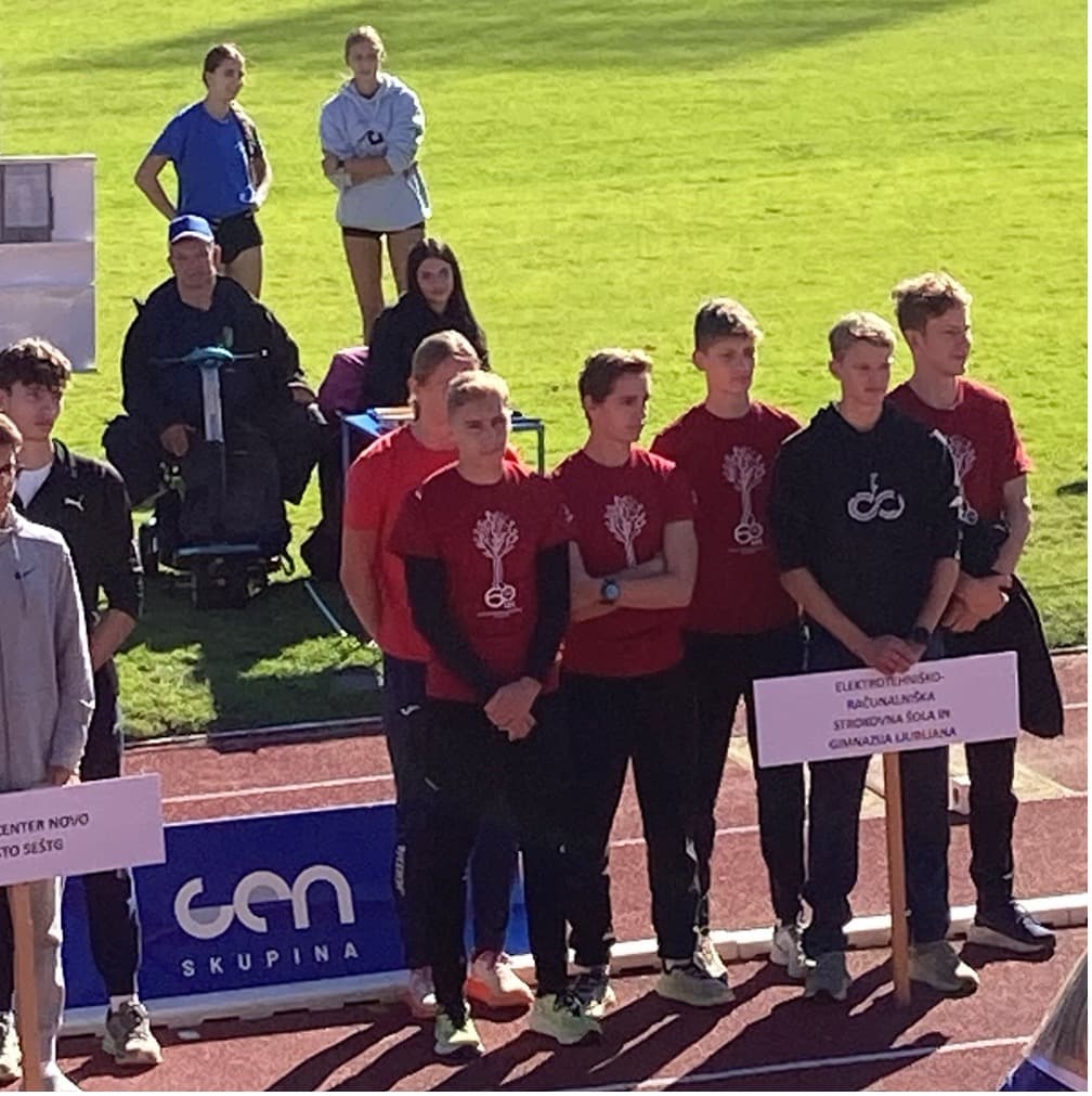 Skupna šestih dijakov na atletski stezi v rdeče črnih športnih oblačilih, na prsih logotip Vegove. Eden od dijakov drži tablo z napisom Elektrotehniško-računalniška strokovna šola in gimnazija Ljubljana