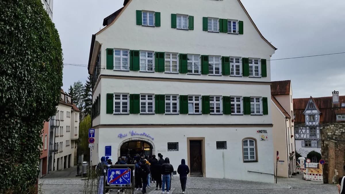 dijaki, ki hodijo proti vhodu v Einsteinov muzej v Ulmu. Ta je v veliki beli hiši s številnimi okni in zelenimi polkni, streha je tipično strma in v obliki črke A